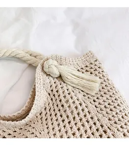 Detail van gehaakte katoenen strandtas met touwhandvatten en een kwastje als hanger