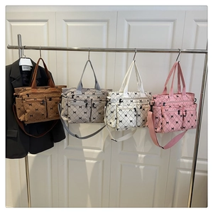 Detail of corduroy tote bags with bow patterns and dual front zipper pockets on display