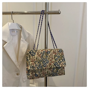 Nahaufnahme der floralen Sticktextur und Goldkette am Schulterriemen der Stofftasche