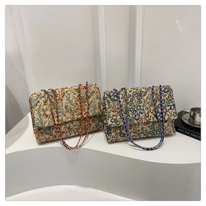 Detail der floralen Jacquard-Stickerei und Metallkettenriemen an den modischen Umhängetaschen