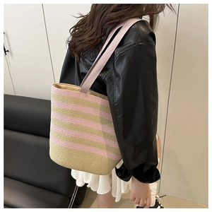 Pink and beige striped woven tote bag with canvas straps shown on model side view