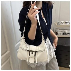 White glossy crescent bag featuring metal buckle and decorative zippers in a lifestyle shot