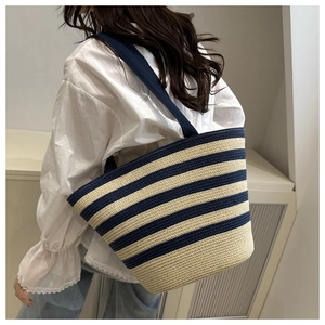 Vue latérale d'un grand sac cabas tissé à rayures bleues et beige pour un look de vacances