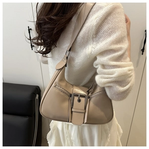 Detail of beige hobo bag showing silver buckle strap and smooth leather texture on a shoulder