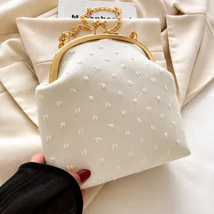 Detail of white textured polka dot fabric and gold metal frame on an elegant evening bag