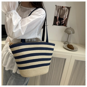 Detail of blue and white striped straw woven tote bag showing texture and slim shoulder strap