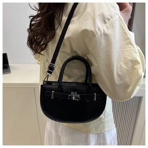 Détail d'un sac à main demi-lune noir avec fermoir rotatif en métal argenté et bandoulière