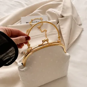 Detail of off-white retro textured clutch bag with gold metal handle and chain strap