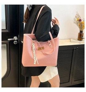 Detail of pink faux crocodile leather tote bag with brand patch and striped tassel