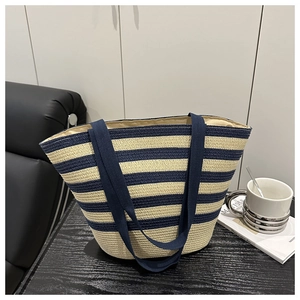 Close-up of a large striped woven straw tote bag on a dark wood table for vacation