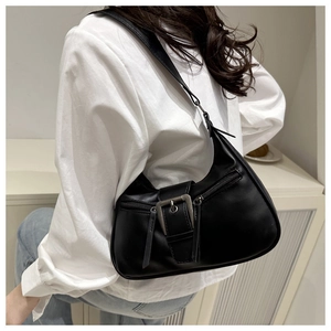 Detail of black crescent shoulder bag featuring vintage metal buckle and leather tassels