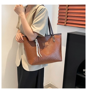 Detailed texture of brown woven tote bag with PU leather brand tag and rope tassels