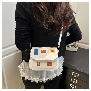 Vue détaillée du sac besace blanc en similicuir avec des écussons colorés de mode