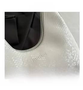 Close-up of white snake-embossed faux leather bag with zipper and inner grey lining