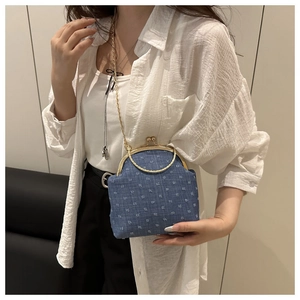 Detail of vintage blue denim crossbody bag with gold kiss-lock and metal chain strap