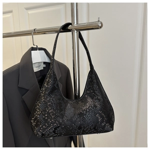Detail of black snakeskin pattern on a half-moon shoulder bag with metal feet
