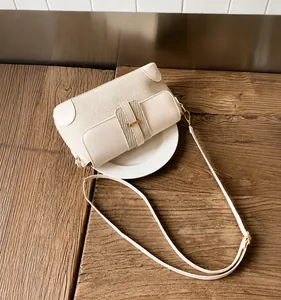 Detail of cream woven shoulder bag featuring textured panels and gold metal buckle strap
