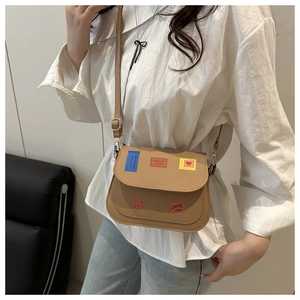 Detail of tan crossbody bag featuring colorful rabbit patches and fine stitching