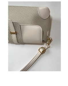 Detailed macro view of herringbone texture and white leather trim with gold hardware