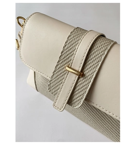 Detail of cream leather and woven texture mix with a golden cylindrical buckle clasp