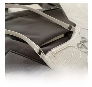 Detail of white crocodile pattern shoulder bag with silver bow hardware and metal ring