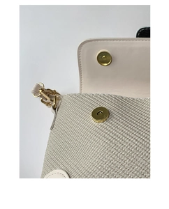 Detailed close-up of textured woven fabric and golden magnetic buckle on baguette bag