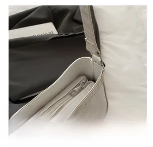 Detail of smooth silver zipper on a white crocodile pattern shoulder bag for women