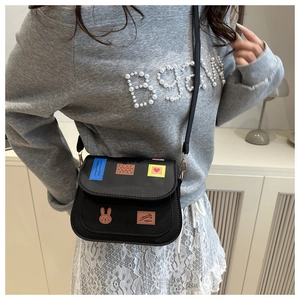 Detail einer schwarzen PU-Leder Satteltasche mit bunten Graffiti-Patches am Modell