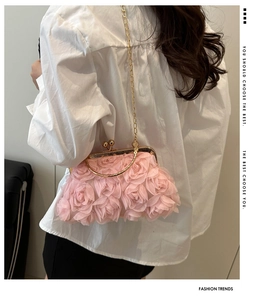 Detail of pink floral evening clutch with golden chain handle on model white shirt