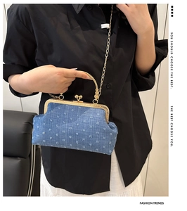 Détail du sac coquillage en denim bleu avec fermoir baiser et chaîne dorée sur mannequin