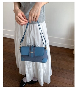 Detail of blue patchwork shoulder bag with fine fabric, leather trim and gold buckle