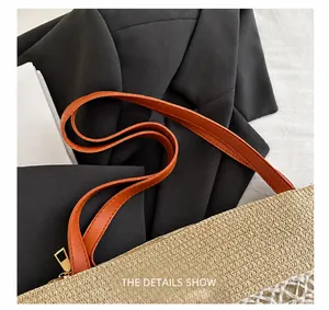 Detail of straw tote with brown faux leather strap and golden zipper closure
