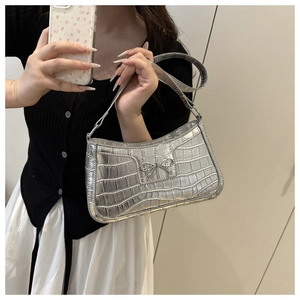 Detail of silver crocodile pattern shoulder bag with a metallic Y2K bow decoration