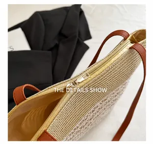 Detail shot of smooth gold zipper and brown leather strap on straw tote bag