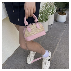 Vue extérieure d'un sac coquillage en paille avec garniture en cuir rose et détails