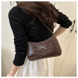 Detail showing brown crocodile-embossed glossy leather with a silver metal bow buckle