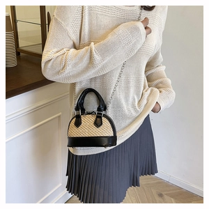 Gros plan d'un mini sac coquillage en paille avec bordure en cuir et chaîne en métal