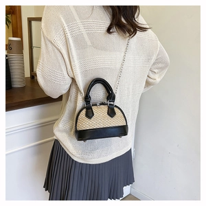 Détail arrière d'un mini sac coquillage en paille tressée avec finitions en cuir noir