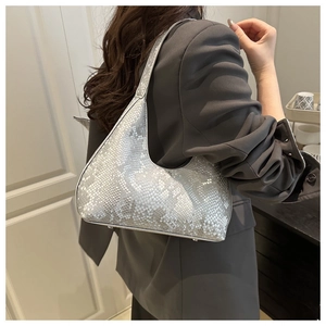 Detail of silver snake skin texture on a hobo shoulder bag worn with a gray blazer