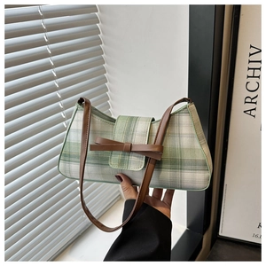 Detail der grün-weiß karierten Schultertasche mit Lederschleife und Trageriemen
