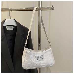 Detail of white crocodile embossed baguette bag with silver bow buckle and shoulder strap