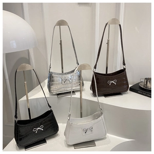Detailed display of four faux crocodile leather shoulder bags with metal bow decorations