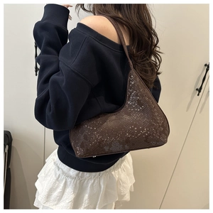 Detail of dark brown faux leather shoulder bag with glossy snake-skin textured surface