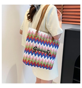 Close-up of a handmade wavy straw tote bag with Summer embroidery on a model
