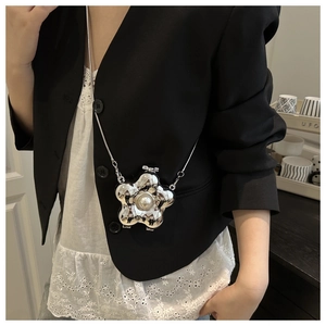 Vista detallada del mini bolso de metal plateado con forma de flor, perla y cadena fina