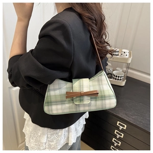 Detail of green plaid tweed underarm bag with brown leather strap and bow decoration