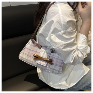 Detail of pink and grey checkered fabric underarm bag with decorative brown leather bow