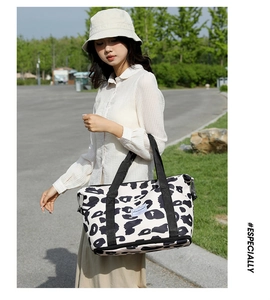 Close-up of leopard print canvas bucket bag with wide black handles and woven logo label