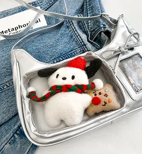 Silver ita-bag detail with clear window displaying plush toy and metallic bow accent