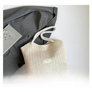 Close-up of a woven tote bag featuring white rope handles and a fashion label detail